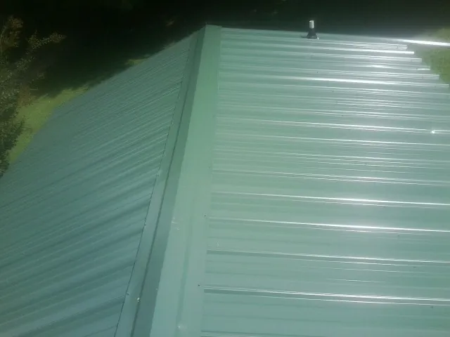 New green metal panels meeting at the ridge of a roof — Flat Roof Repair work by our crew in Blackwood