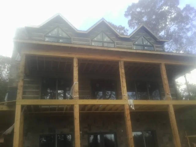 Dormers and porch framing on a large log home under construction — Roof Coating work by our crew in Blackwood
