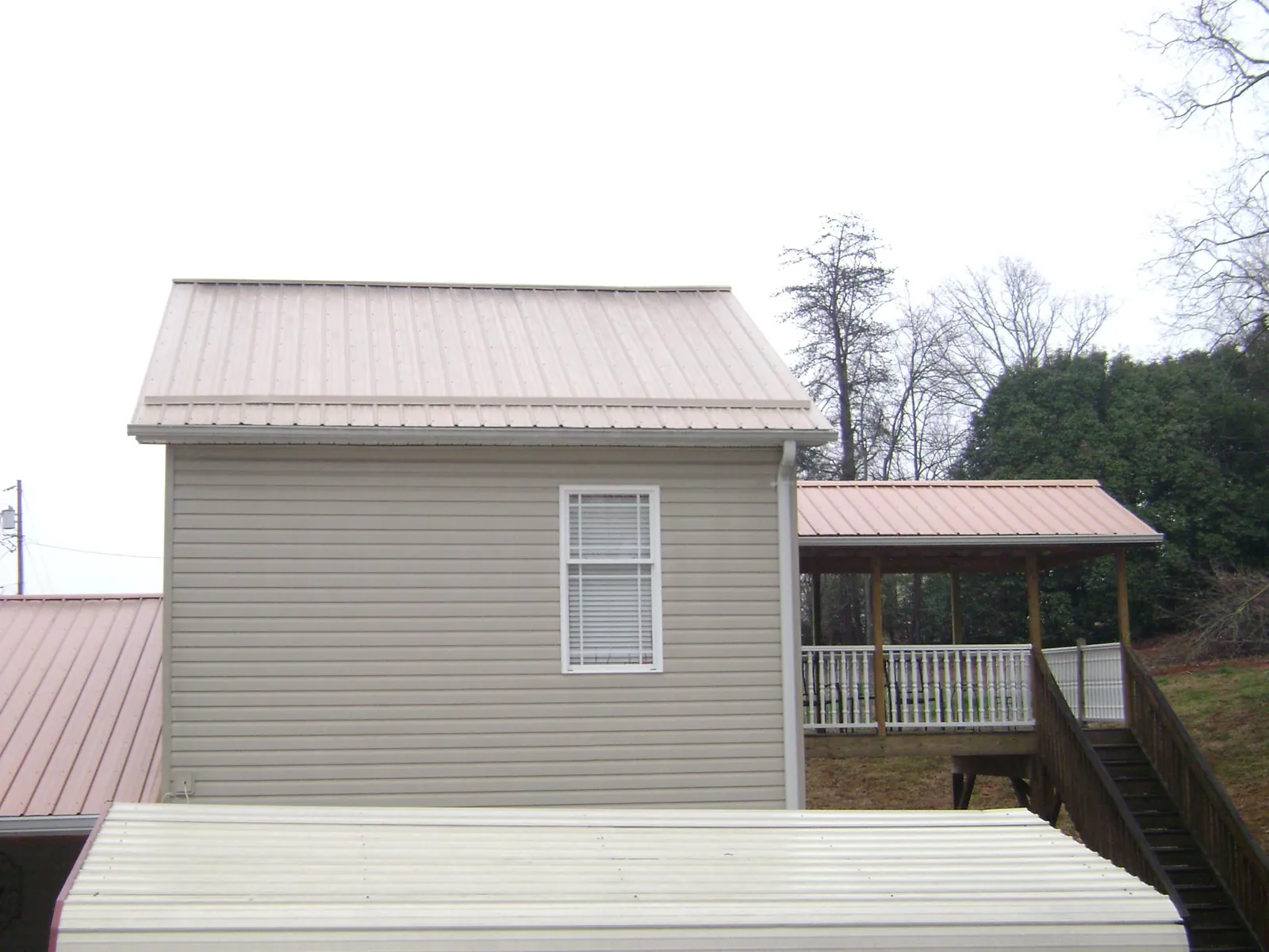 Tan metal roofs on a two story addition and attached porch, from a Roof Replacement job in Blackwood