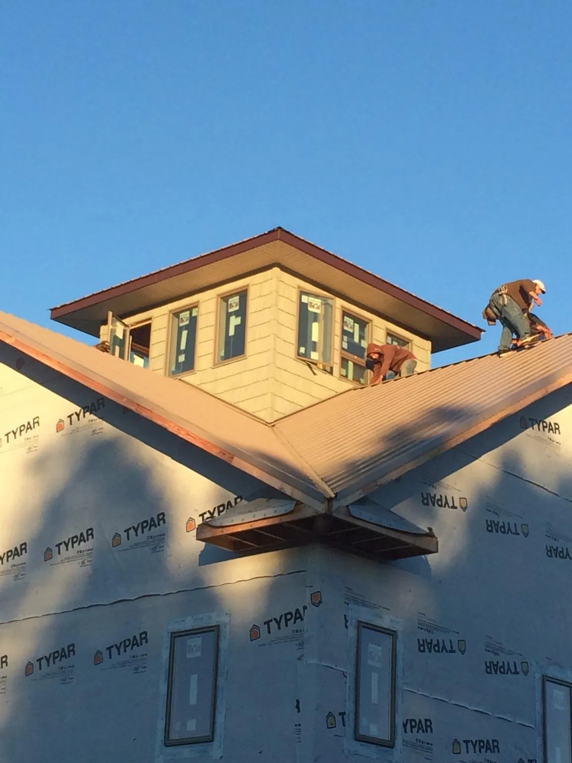 Roofers working around a rooftop cupola on a new metal roof at sunset — Roof Waterproofing in Blackwood by Roofing Brothers